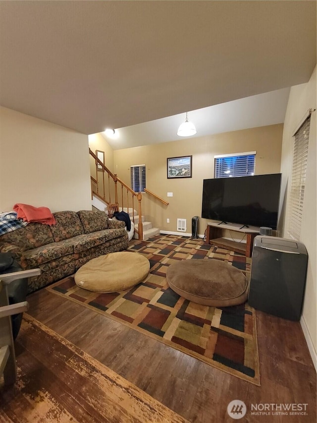living room with wood finished floors, baseboards, visible vents, and stairs