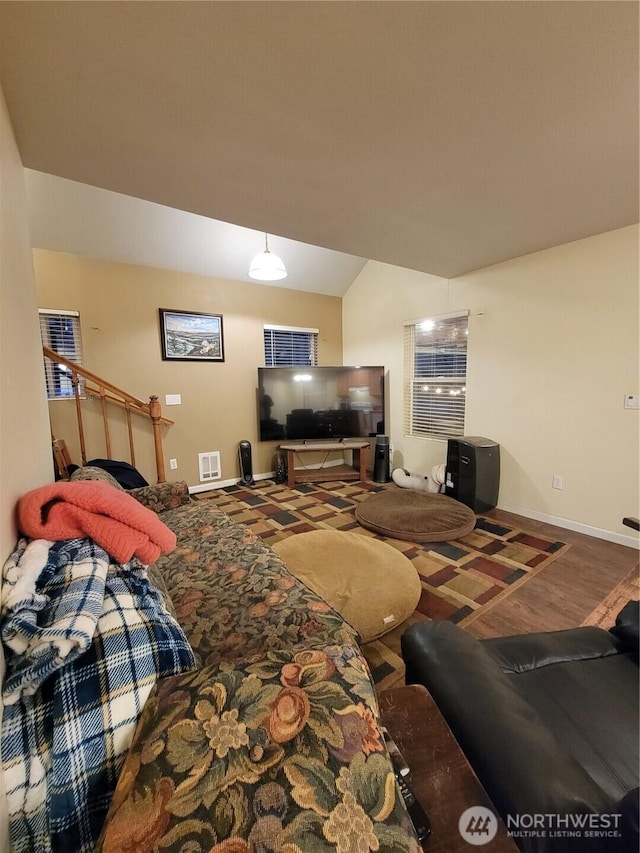 living area featuring visible vents, baseboards, wood finished floors, and lofted ceiling