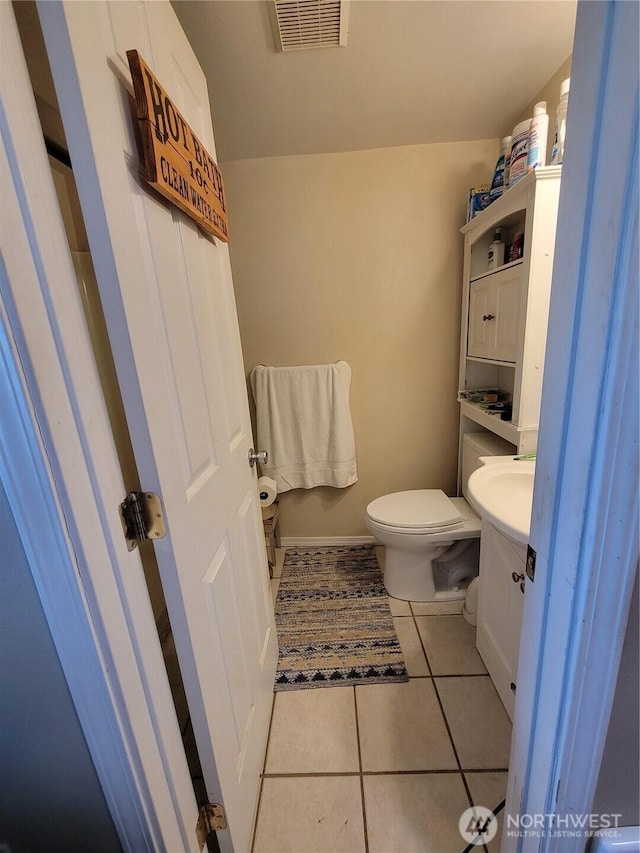 half bath featuring visible vents, baseboards, toilet, vanity, and tile patterned flooring