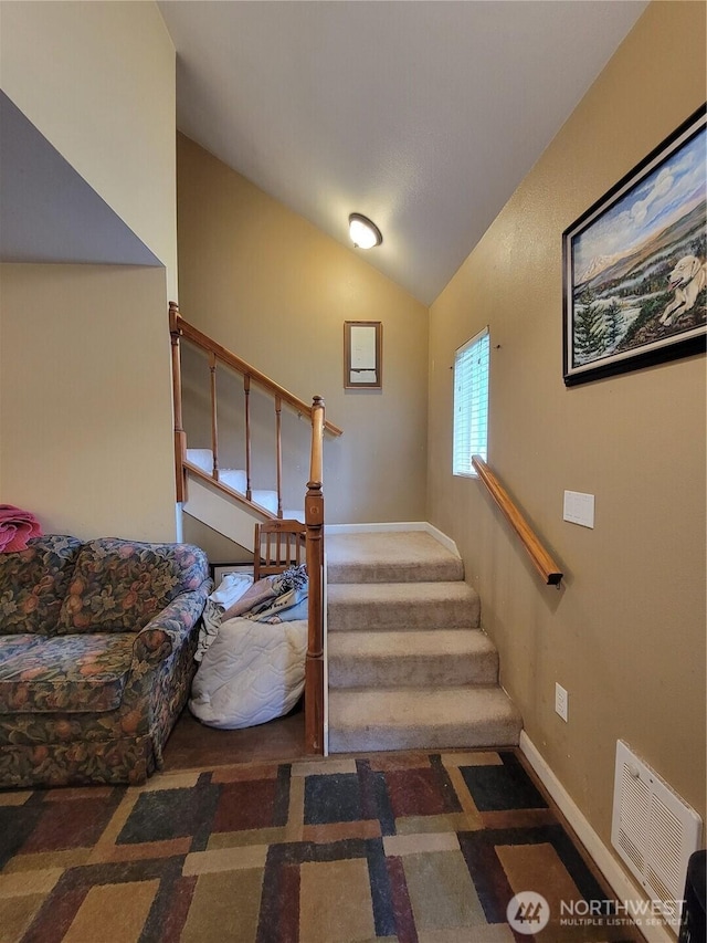 stairway with visible vents, baseboards, lofted ceiling, and carpet floors