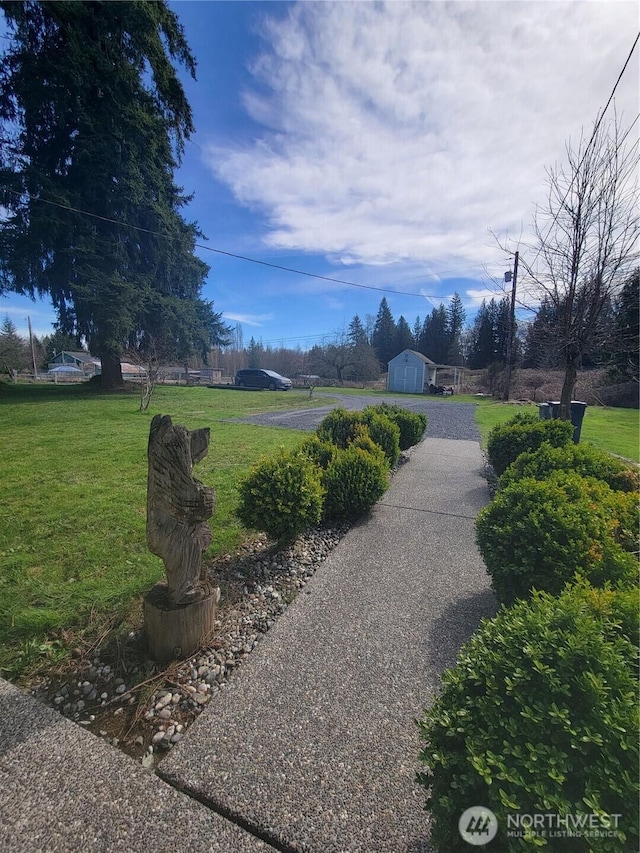 view of property's community with a yard and an outdoor structure