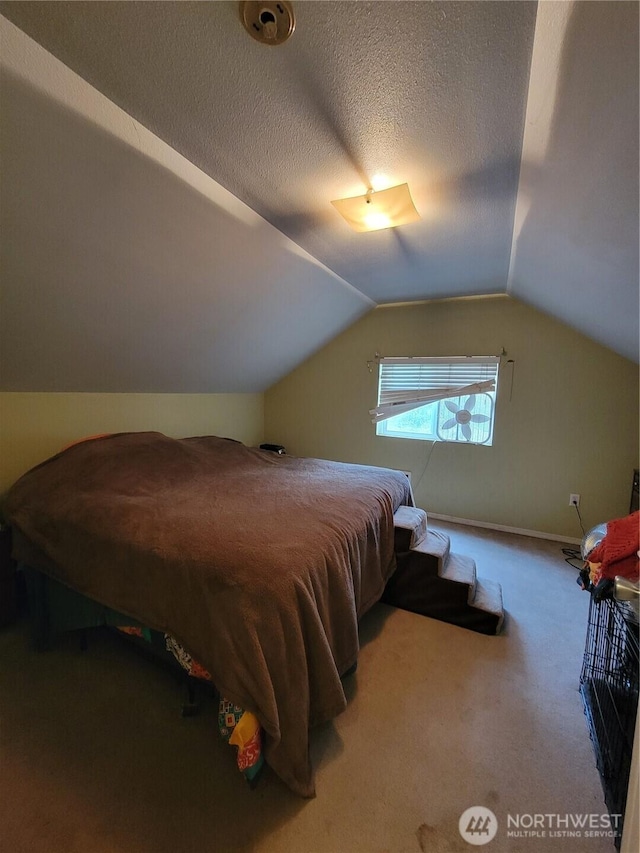 bedroom with a textured ceiling, vaulted ceiling, and carpet floors