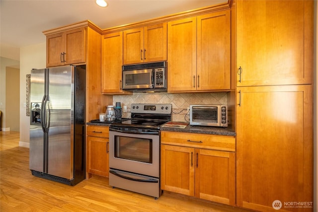 660 Parkside Pl, Blaine, WA 98230 - kitchen with light wood-style flooring, appliances with stainless steel finishes, dark countertops, decorative backsplash, and a toaster