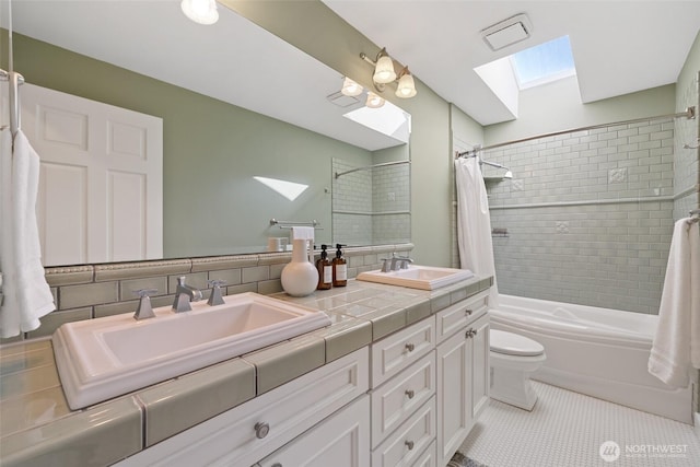 bathroom featuring tile patterned floors, shower / bath combination with curtain, a sink, and a skylight