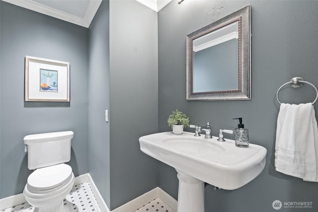 bathroom with baseboards, ornamental molding, and toilet