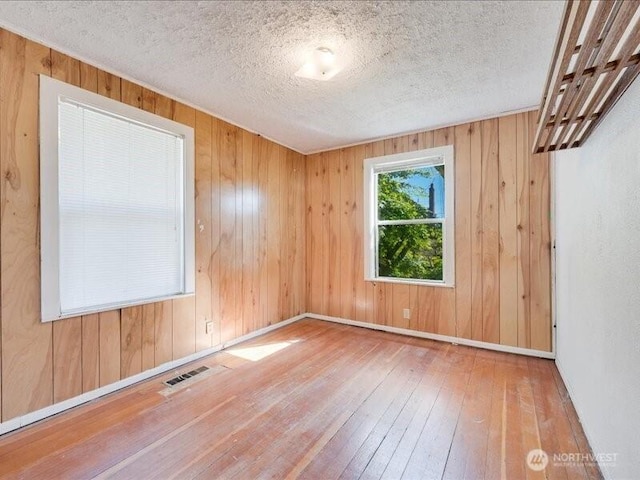 8434 34th Ave S, Seattle, WA 98118 - unfurnished room with hardwood / wood-style floors, wood walls, a textured ceiling, and baseboards