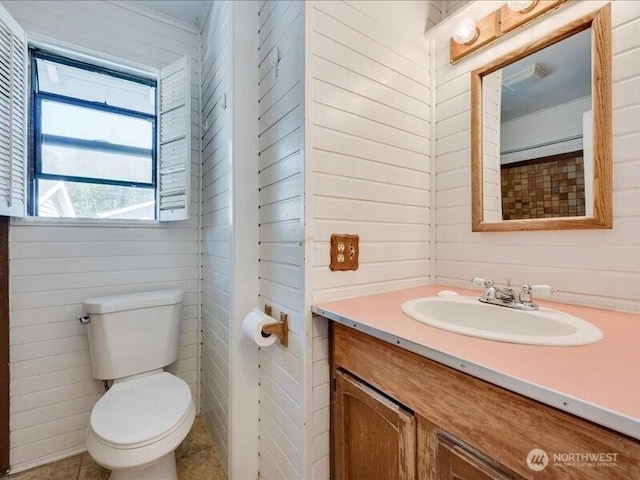 8434 34th Ave S, Seattle, WA 98118 - bathroom featuring toilet, vanity, tile patterned floors, and wooden walls