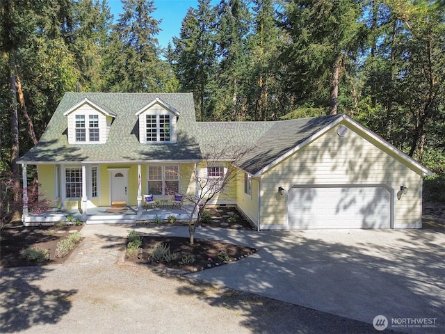 861 Kirner Rd, Sequim, WA 98382 - cape cod house featuring covered porch, a garage, driveway, roof with shingles, and view of scattered trees