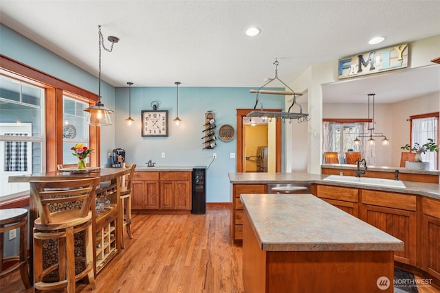 14900 NE Critter Hill Dr, Amboy, WA 98601 - kitchen with a sink, brown cabinets, light wood-style floors, a kitchen island, and pendant lighting
