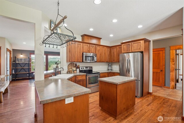 14900 NE Critter Hill Dr, Amboy, WA 98601 - kitchen featuring appliances with stainless steel finishes, a sink, a peninsula, a kitchen island, and brown cabinets