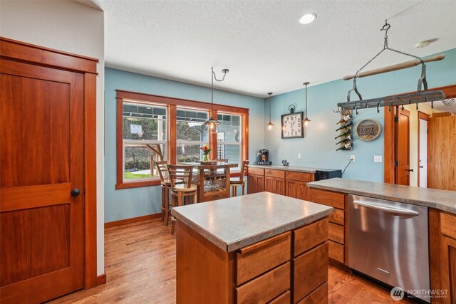 14900 NE Critter Hill Dr, Amboy, WA 98601 - kitchen with stainless steel dishwasher, brown cabinetry, a textured ceiling, a center island, and light wood-style flooring