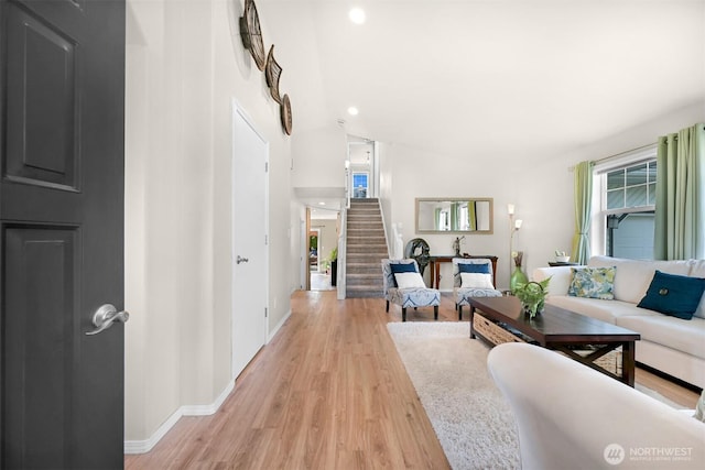 living area with light wood-type flooring, baseboards, plenty of natural light, and stairs