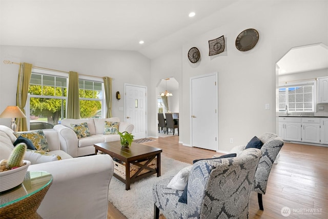 living room featuring high vaulted ceiling, recessed lighting, arched walkways, and light wood-style floors