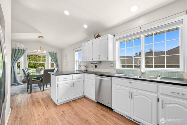 kitchen with stainless steel dishwasher, an inviting chandelier, a peninsula, a sink, and lofted ceiling