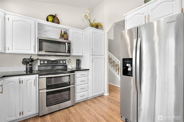 kitchen featuring light wood-type flooring, dark countertops, white cabinets, and stainless steel appliances