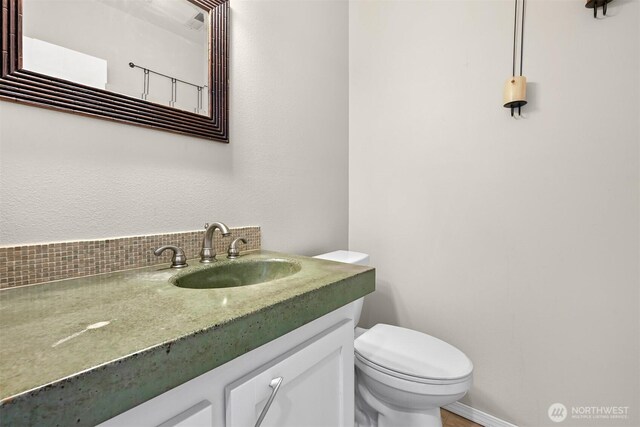 half bath with toilet, vanity, and baseboards