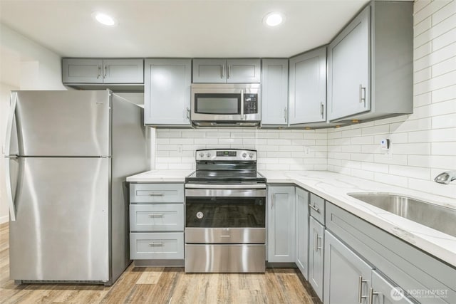 201 S 60th St, Tacoma, WA 98408 - kitchen with a sink, appliances with stainless steel finishes, light wood finished floors, gray cabinets, and light stone counters