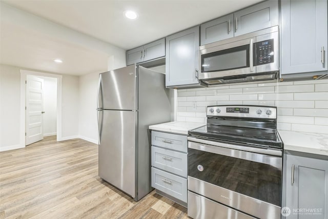 201 S 60th St, Tacoma, WA 98408 - kitchen with baseboards, appliances with stainless steel finishes, gray cabinets, light wood-style flooring, and decorative backsplash