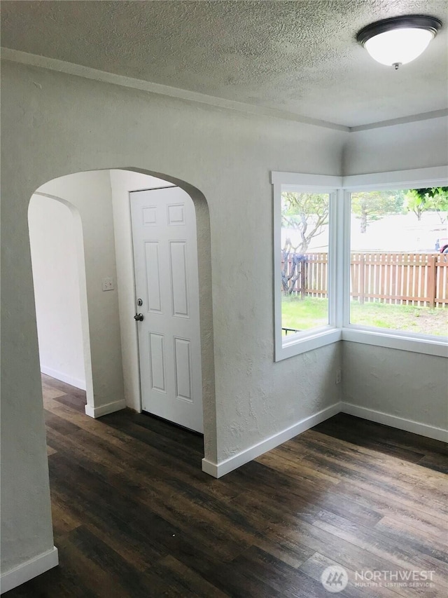 201 S 60th St, Tacoma, WA 98408 - spare room featuring arched walkways, baseboards, and dark wood finished floors