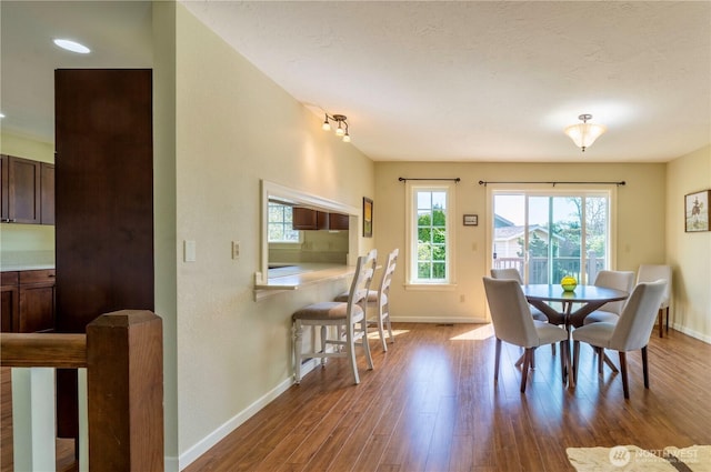 dining space with baseboards and wood finished floors