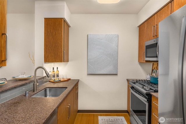 413 NE 70th St Unit 402, Seattle, WA 98115 - kitchen featuring a sink, wood finished floors, brown cabinetry, stainless steel appliances, and baseboards