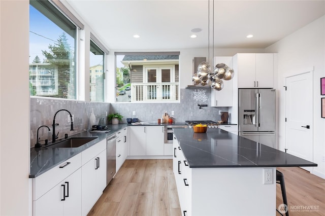 3111 Queen Anne Ave N, Seattle, WA 98119 - kitchen featuring wall chimney exhaust hood, appliances with stainless steel finishes, a sink, dark countertops, and light wood finished floors