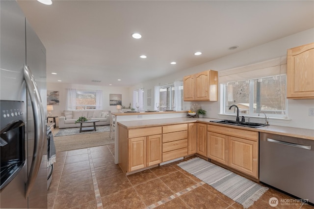 kitchen featuring a peninsula, light brown cabinetry, recessed lighting, a sink, and stainless steel appliances