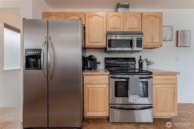 kitchen with appliances with stainless steel finishes, light brown cabinetry, and tile patterned flooring