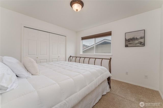 bedroom with a closet, light colored carpet, and baseboards