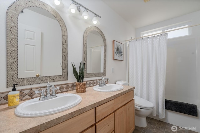 bathroom with tile patterned flooring, double vanity, a sink, and toilet