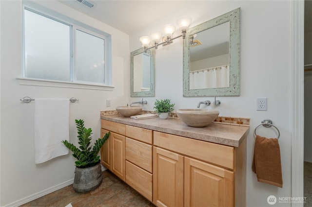 bathroom featuring double vanity, visible vents, baseboards, and a sink
