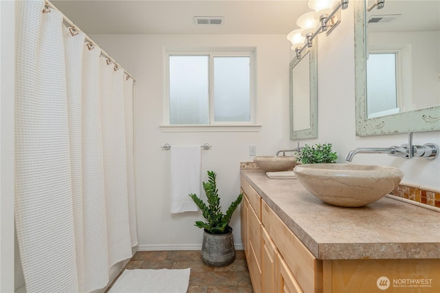 full bath featuring a wealth of natural light, vanity, visible vents, and baseboards