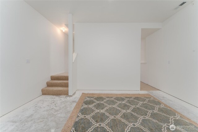 empty room featuring visible vents, carpet, and stairs