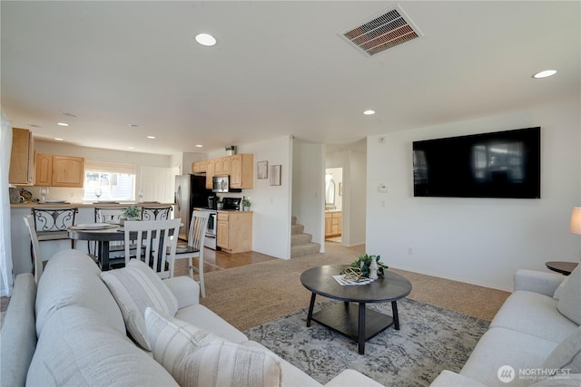 living area featuring visible vents, baseboards, recessed lighting, and light colored carpet