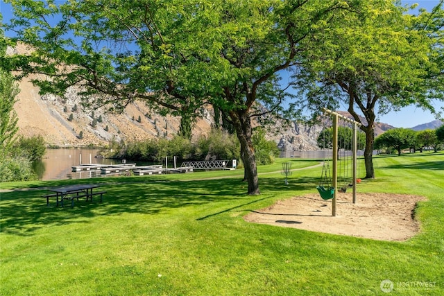 view of home's community featuring a mountain view, playground community, and a lawn