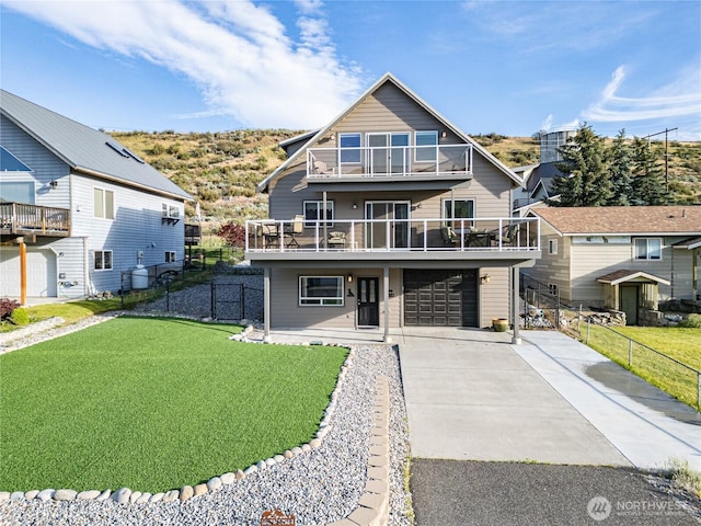 chalet / cabin with a garage, fence, a balcony, a front lawn, and driveway