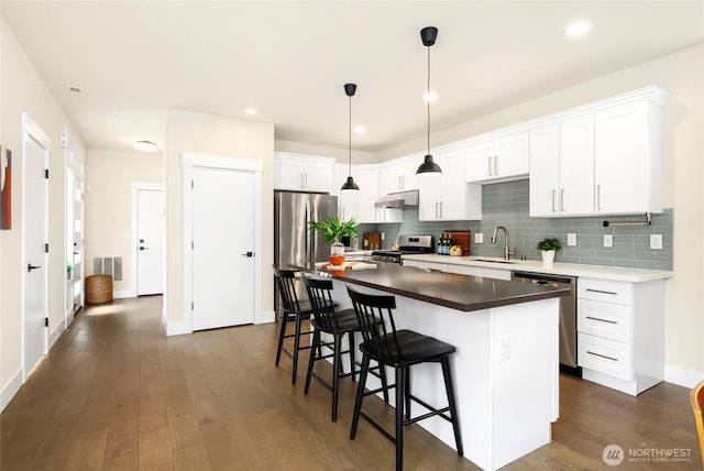 10410 2nd Pl SW, Seattle, WA 98146 - kitchen featuring a kitchen island, backsplash, appliances with stainless steel finishes, a sink, and dark wood-style floors