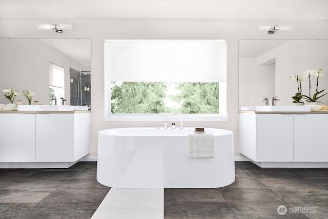 full bathroom featuring a sink, two vanities, a soaking tub, and a stall shower