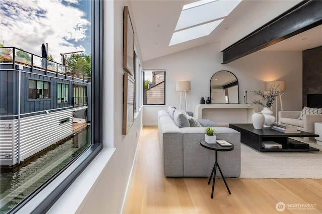 living area with vaulted ceiling with skylight and wood finished floors