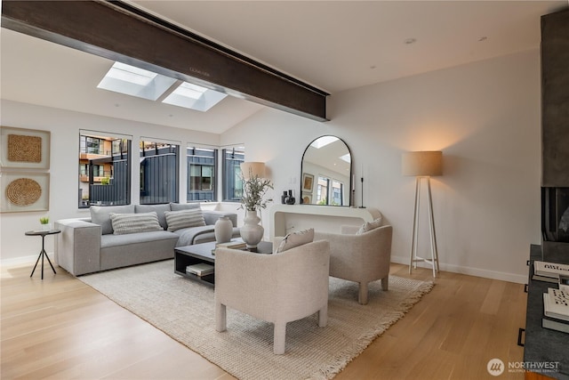 interior space with baseboards, lofted ceiling with skylight, and wood finished floors