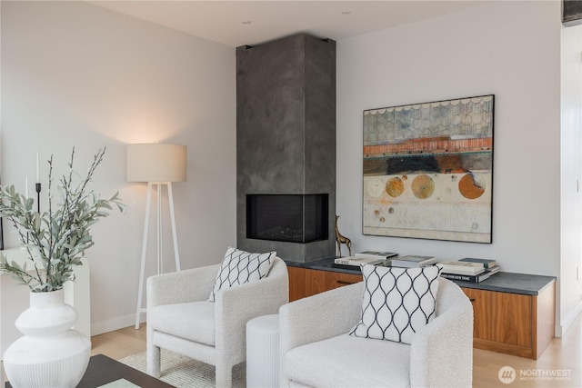 living area with baseboards, a fireplace, and light wood-type flooring