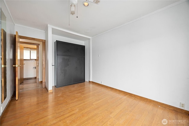 unfurnished bedroom with crown molding, baseboards, light wood finished floors, and a closet