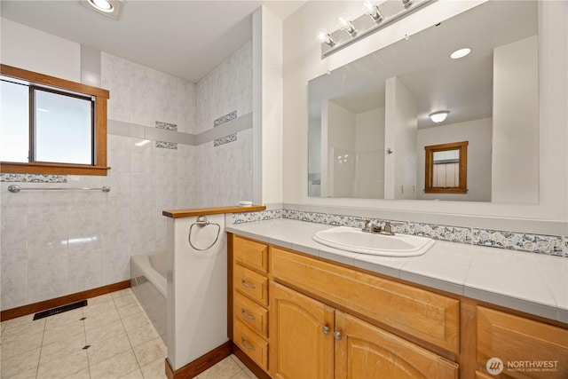 bathroom with a bathing tub, walk in shower, tile patterned flooring, and vanity