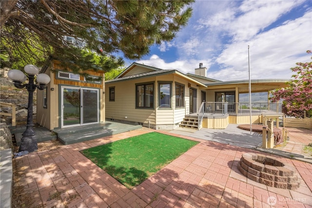 rear view of house with a patio, a chimney, and an outdoor fire pit