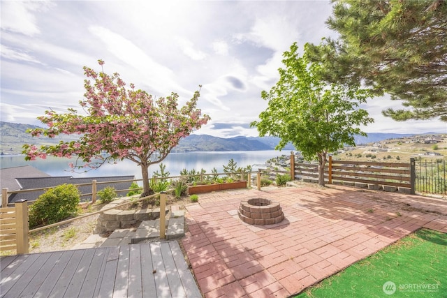 view of patio / terrace with fence, a fire pit, and a water and mountain view