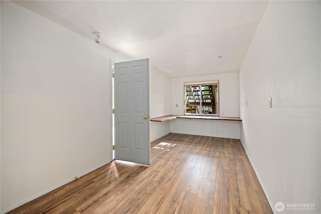 spare room featuring baseboards and wood finished floors