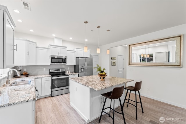 11232 Crescent Valley Dr NW, Gig Harbor, WA 98332 - kitchen featuring tasteful backsplash, a kitchen island, a sink, stainless steel appliances, and light wood finished floors