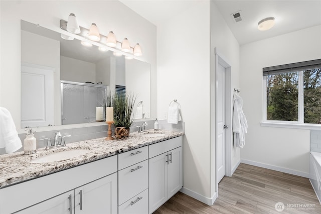 11232 Crescent Valley Dr NW, Gig Harbor, WA 98332 - full bathroom with baseboards, double vanity, a shower stall, a sink, and wood finished floors