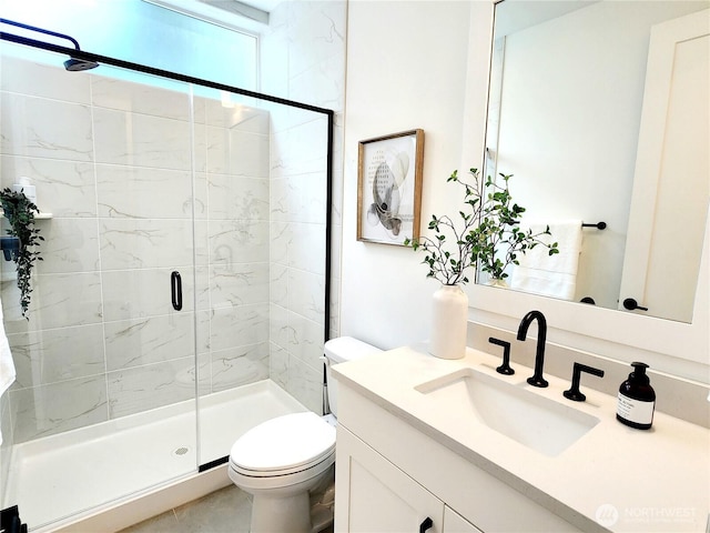 bathroom with vanity, a shower stall, and toilet