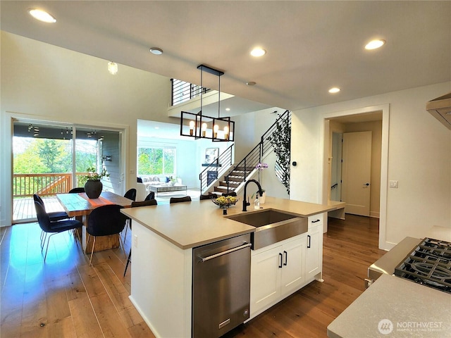 kitchen featuring a sink, hardwood / wood-style floors, white cabinetry, stainless steel dishwasher, and pendant lighting